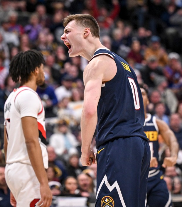 Christian Braun (0) of the Denver Nuggets flexes after drawing a foul from Anfernee Simons (1) of the Portland Trail Blazers during the fourth quarter of the Nuggets' 132-121 win at Ball Arena in Denver on Feb. 12, 2025. (Photo by AAron Ontiveroz/The Denver Post)
