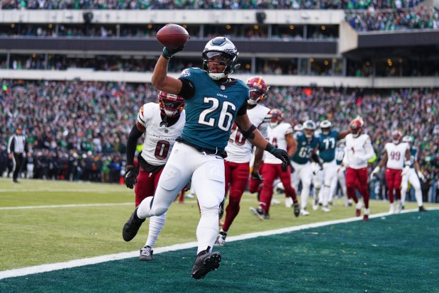 Philadelphia Eagles running back Saquon Barkley (26) scores a touchdown as Washington Commanders cornerback Mike Sainristil (0) chases him during the first half of the NFC Championship NFL football game, Sunday, Jan. 26, 2025, in Philadelphia. (AP Photo/Derik Hamilton)