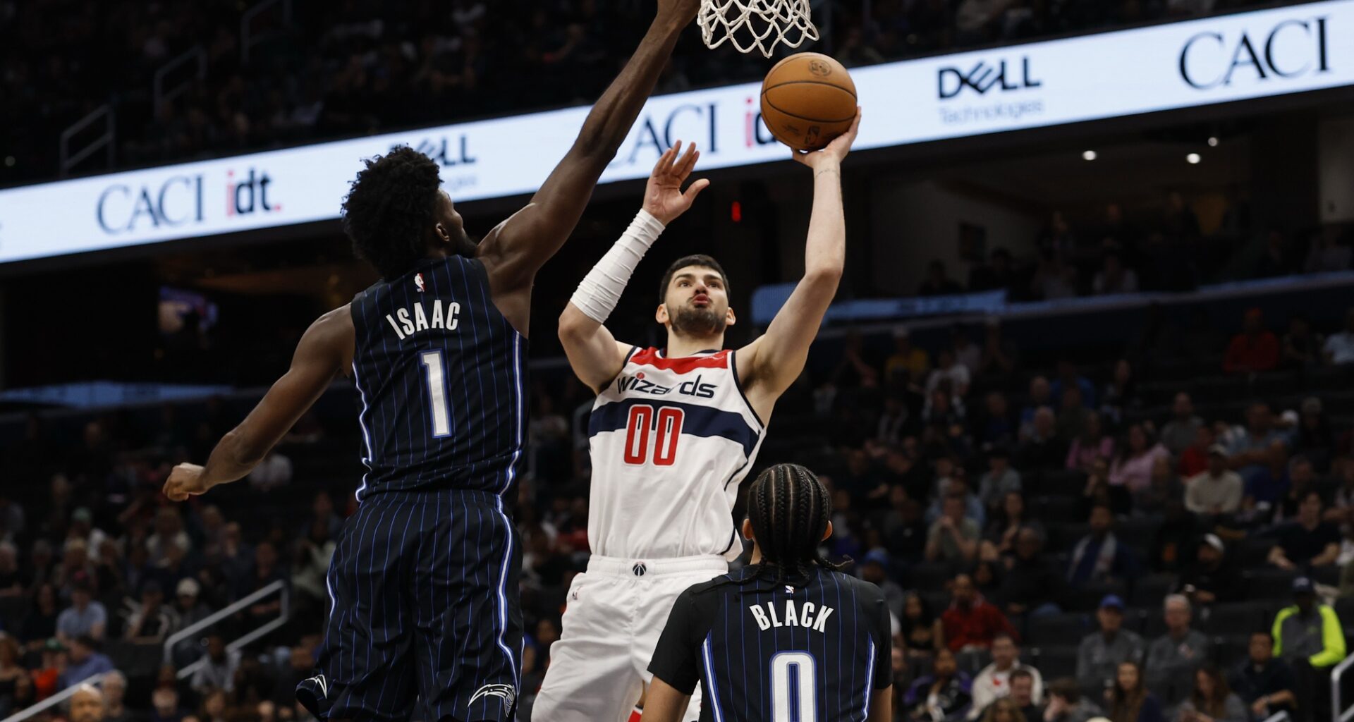 Apr 3, 2025; Washington, District of Columbia, USA; Washington Wizards forward Tristan Vukcevic (00) shoots the ball as Orlando Magic forward Jonathan Isaac (1) defends in the second half at Capital One Arena. Mandatory Credit: Geoff Burke-Imagn Images