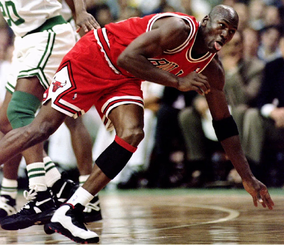 Michael Jordan of the Chicago Bulls falls to the court with his tongue out as he is pushed down by Sherman Douglas of the Boston Celtics in 1st quarter action at Boston Garden, March 22. The game is Jordan's second since returning to the NBA. Chicago went on to win 124 to 107