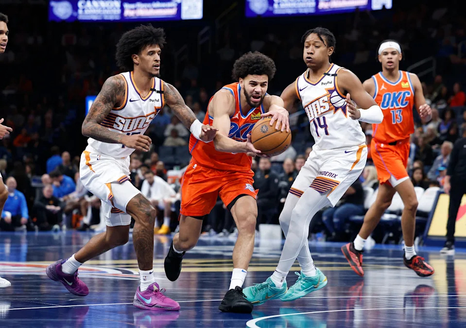 Nov 15, 2024; Oklahoma City, Oklahoma, USA; Oklahoma City Thunder guard Ajay Mitchell (25) drives to the basket between Phoenix Suns forward Jalen Bridges (15) and guard TyTy Washington Jr. (14)during the fourth quarter at Paycom Center. Mandatory Credit: Alonzo Adams-Imagn Images