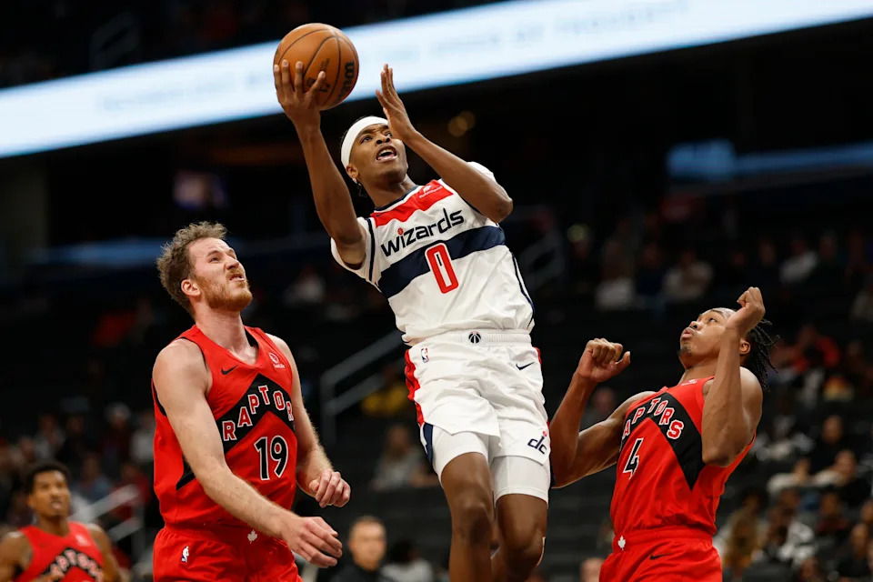 Oct 11, 2024; Washington, District of Columbia, USA; Washington Wizards guard Bilal Coulibaly (0) shoots the ball as Toronto Raptors center Jakob Poeltl (19) and Raptors forward Scottie Barnes (4) defend in the second quarter at Capital One Arena. Mandatory Credit: Geoff Burke-Imagn Images
