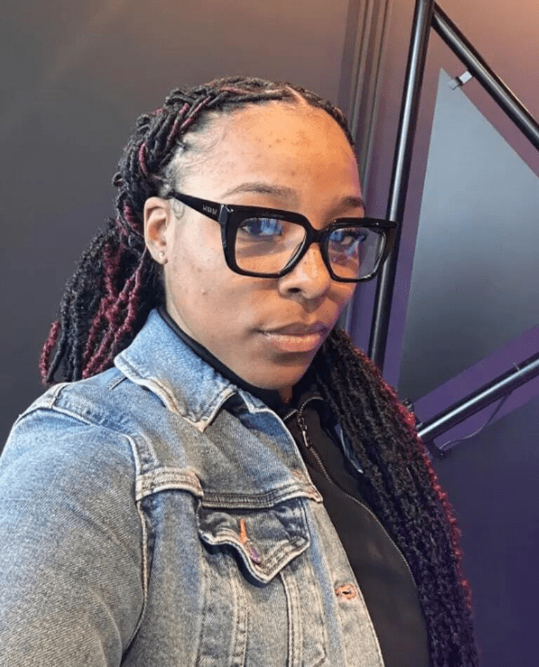 Portrait of a woman wearing glasses and a denim jacket.