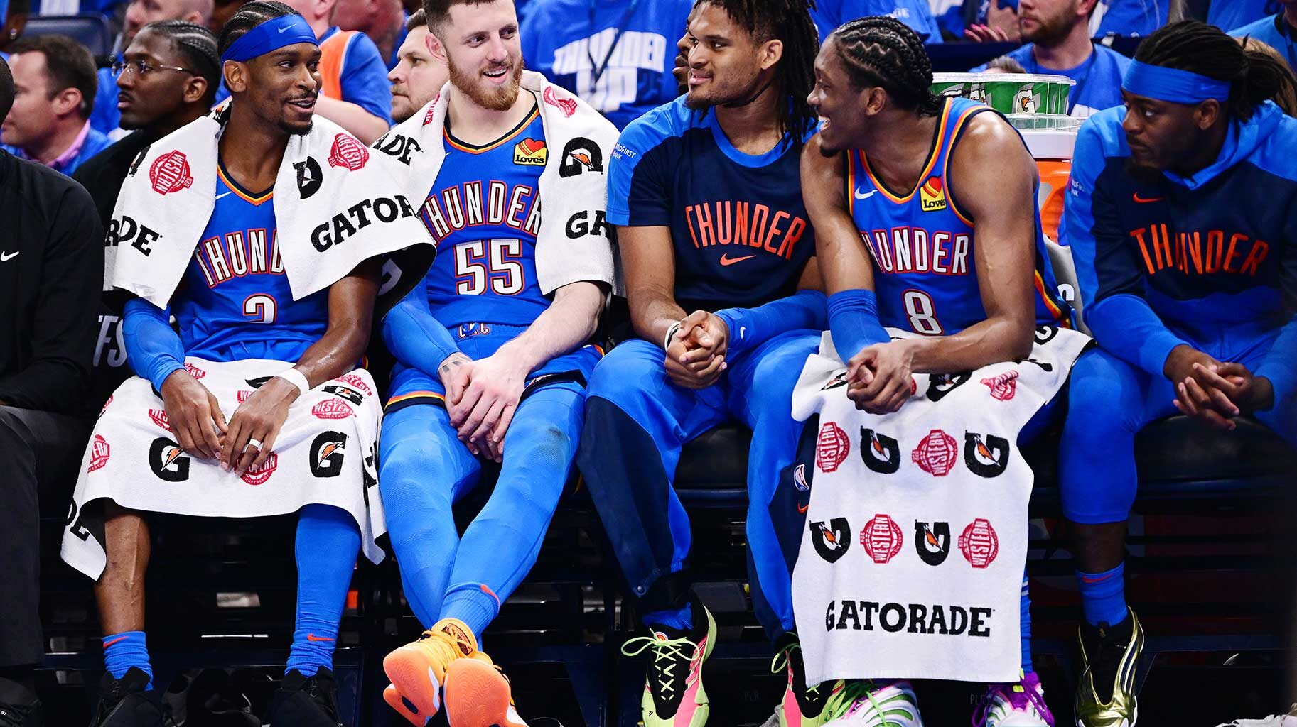 Shai Gilgeous-Alexander, Isaiah Hartenstein, and Jalen Williams of the Oklahoma City Thunder share a laugh on the bench during the fourth quarter of a game against the Denver Nuggets.