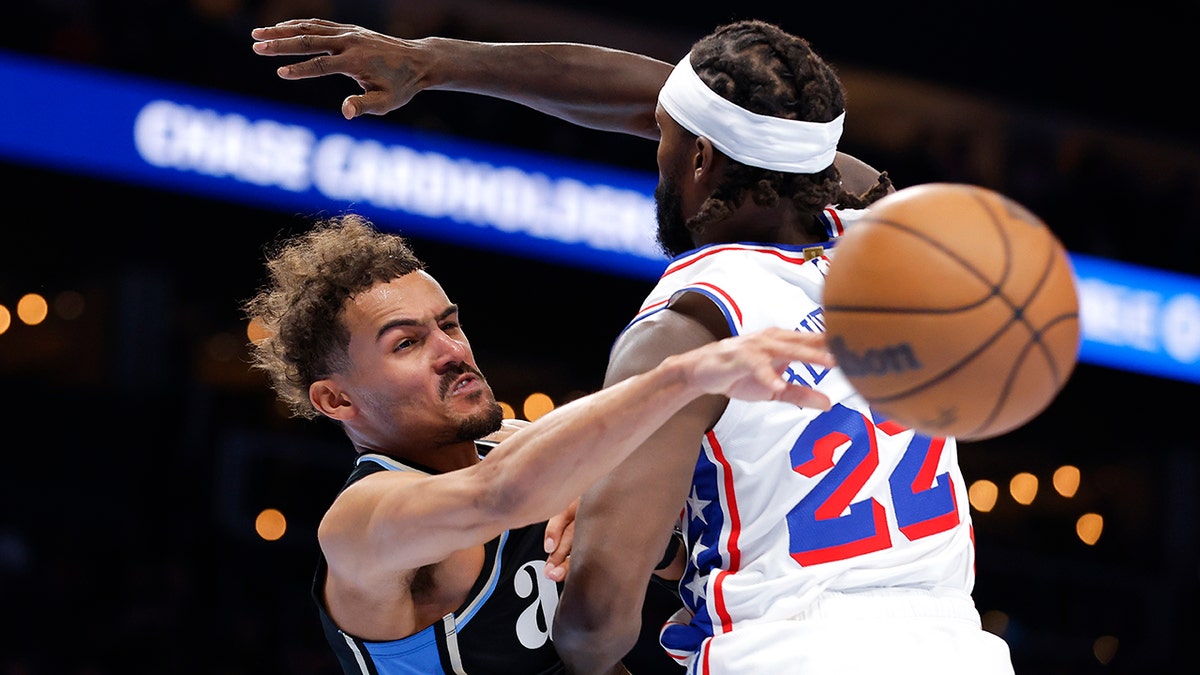 Trae Young passes the ball while being guarded by Patrick Beverley