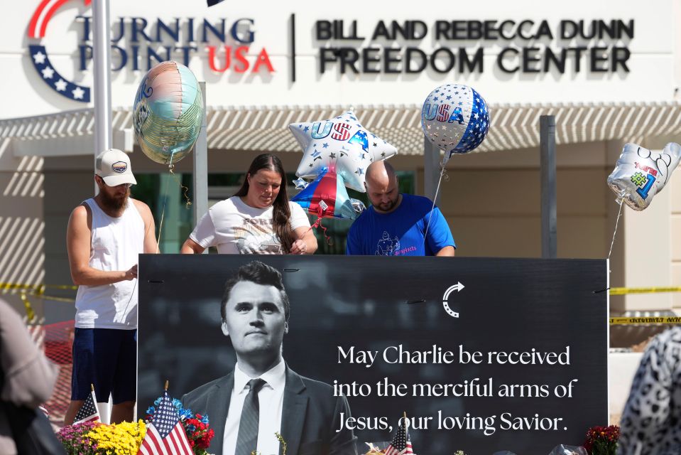 People placing balloons at a memorial for Charlie Kirk outside Turning Point USA headquarters.