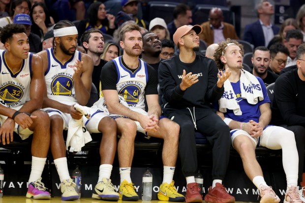 Golden State Warriors' Trayce Jackson-Davis (32), Golden State Warriors' Moses Moody (4), Golden State Warriors' Pat Spencer (61), Golden State Warriors' Seth Curry and Golden State Warriors' Brandin Podziemski (2) look on from the bench as their teammates take on the Portland Trail Blazers in the fourth quarter of an NBA preseason game at Chase Center in San Francisco, Calif., on Wednesday, Oct. 8, 2025. (Ray Chavez/Bay Area News Group) basket