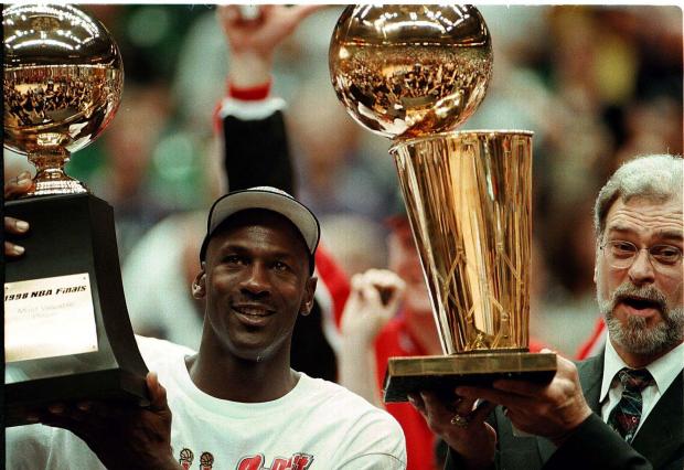 Michael Jordan holds his MVP finals trophy while Phil Jackson holds the NBA championship trophy in 1998. (Phil Velasquez, Phil Velasquez / Chicago Tribune)