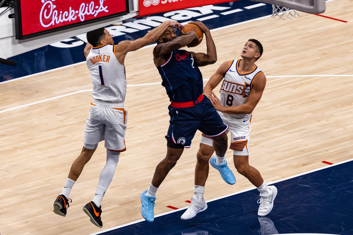 Forward Kawhi Leonard #2 of the LA Clippers is fouled by guard Devin Booker #1 of the Phoenix Suns during an NBA game at the Intuit Dome on October 24, 2025 in Inglewood California.