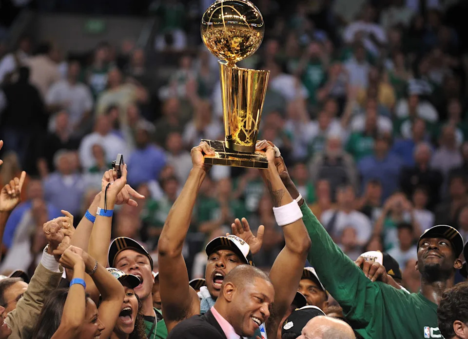 Boston Celtics' Paul Pierce (C) holds the NBA trophy with teammate Kevin Garnett (R) before head coach Doc Rivers (1rst row) after winning Game 6 of the 2008 NBA Finals, in Boston, Massachusetts, June 17, 2008. The Boston Celtics captured the National Basketball Association championship, routing the Los Angeles Lakers 131-92 to win the best-of-seven NBA Finals four games to two. AFP PHOTO / GABRIEL BOUYS (Photo credit should read GABRIEL BOUYS/AFP via Getty Images)