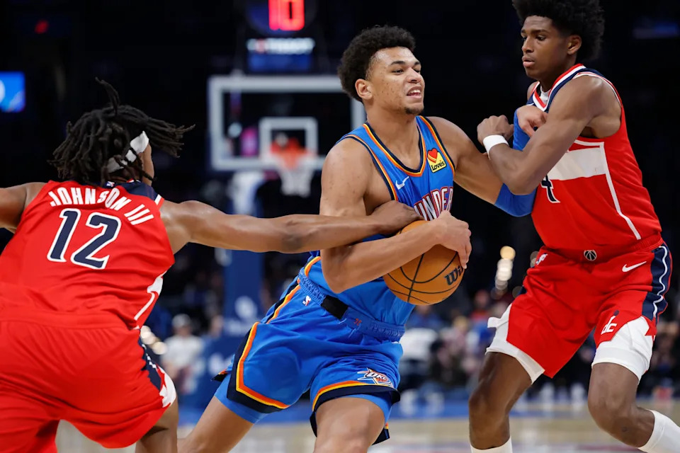 Oct 30, 2025; Oklahoma City, Oklahoma, USA; Oklahoma City Thunder forward Ousmane Dieng (13) drives between Washington Wizards guard Tre Johnson (12) and guard AJ Johnson (4) during the second half at Paycom Center. Mandatory Credit: Alonzo Adams-Imagn Images