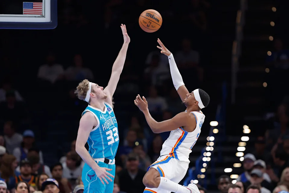 Oct 9, 2025; Oklahoma City, Oklahoma, USA; Oklahoma City Thunder guard Aaron Wiggins (21) shoots as Charlotte Hornets forward Liam McNeeley (33) defends during the second half of a game between the Charlotte Hornets and the Oklahoma City Thunder at Paycom Center. Mandatory Credit: Alonzo Adams-Imagn Images