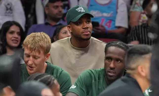 Milwaukee Bucks forward Giannis Antetokounmpo, who is recovering from COVID-19, sits behind his team's bench as he watches the second half of a preseason NBA basketball game against the Miami Heat, Monday, Oct. 6, 2025, in Miami. (AP Photo/Rebecca Blackwell)