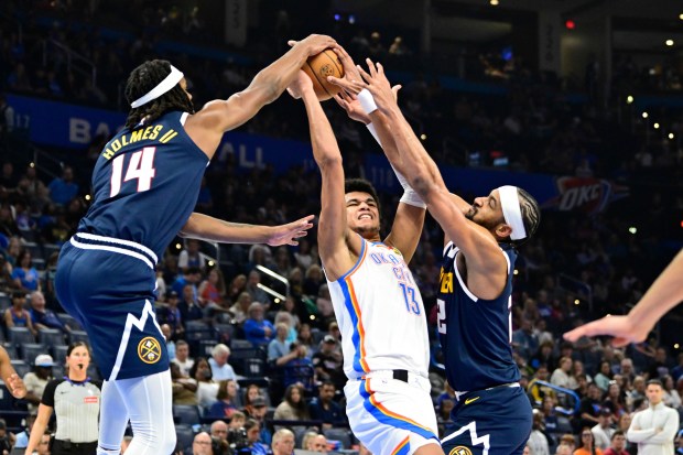 Denver Nuggets forward Daron Holmes II (14) and forward/center Zeke Nnaji, right, block the ball against Oklahoma City Thunder forward Ousmane Dieng (13) during the second half of a preseason NBA basketball game Friday, Oct. 17, 2025, in Oklahoma City. (AP Photo/Gerald Leong)