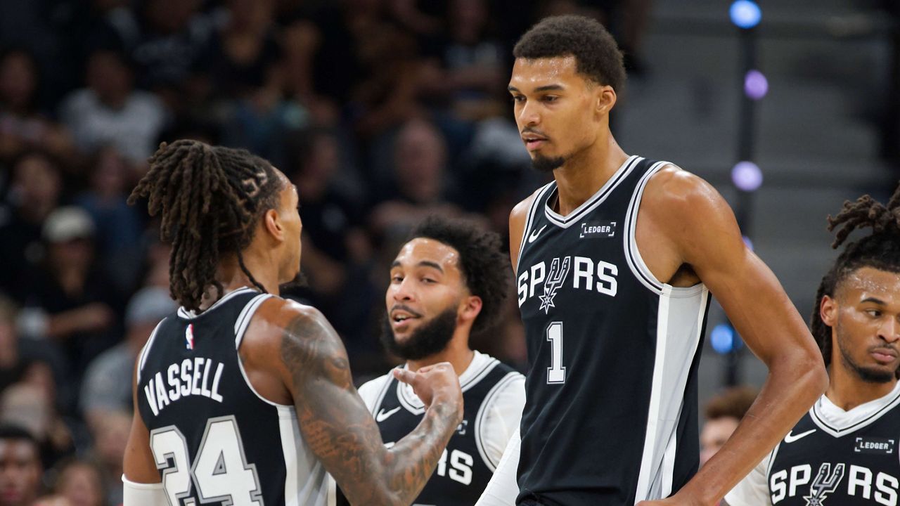 San Antonio Spurs center Victor Wembanyama (1) speaks with Spurs guard Devin Vassell (24) during the first half of their NBA basketball game against the Toronto Raptors, Monday, Oct. 27, 2025, in San Antonio. (AP Photo/Darren Abate)