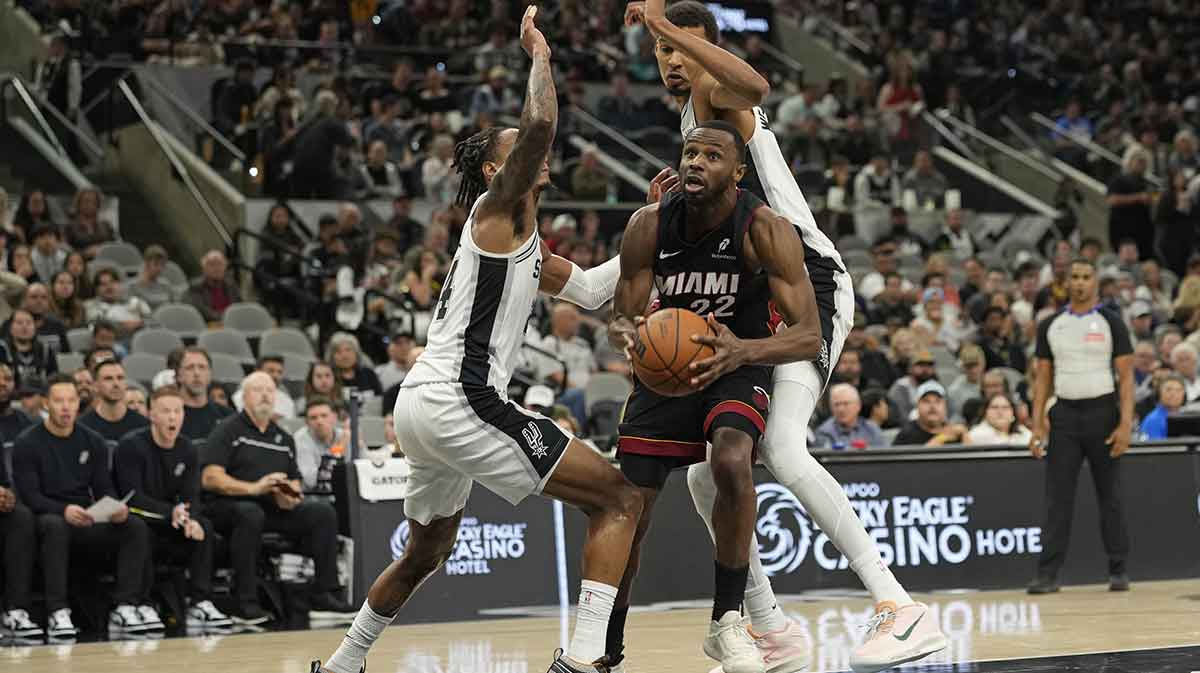 Miami Heat forward Andrew Wiggins (22) drives to the basket between San Antonio Spurs guard Devin Vassell (24) and forward Victor Wembanyama (1) during the second half at Frost Bank Center.