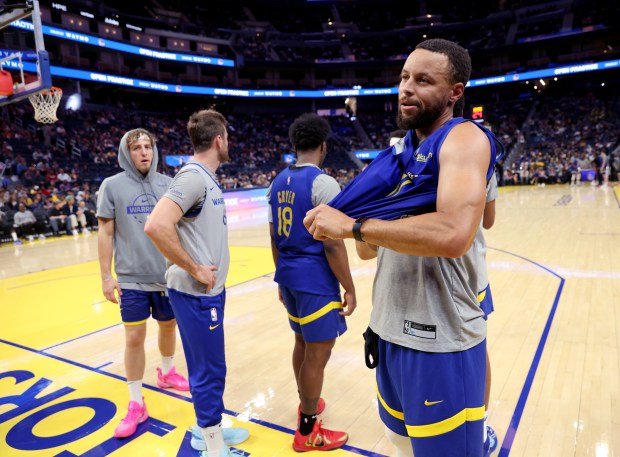 Golden State Warriors' Stephen Curry #30 takes off his shirt...
