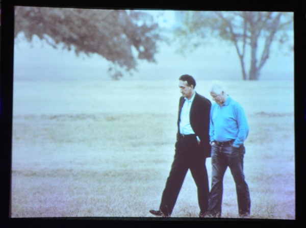 President Clinton and Henry Cisneros walk together. Photo of projected image displayed during banquet.