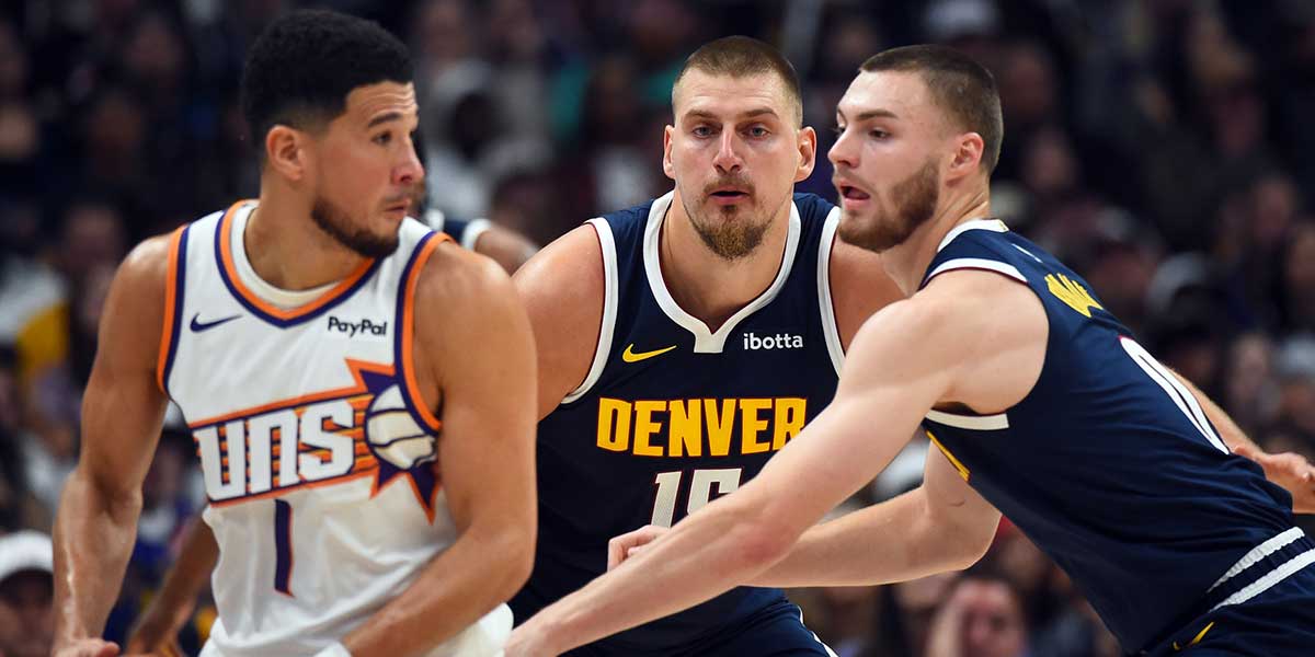 Denver Nuggets center Nikola Jokic (15) and guard Christian Braun (0) defend Phoenix Suns guard Devin Booker (1) during the first half at Ball Arena.