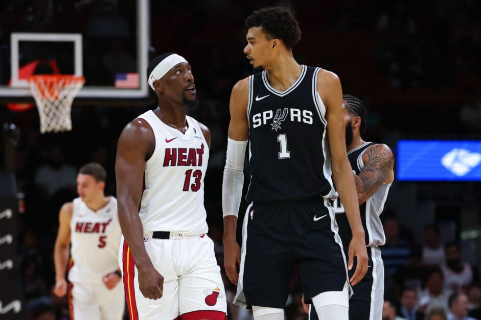 Bam Adebayo #13 of the Miami Heat and Victor Wembanyama #1 of the San Antonio Spurs reacts during the first quarter of a preseason game at Kaseya Center.