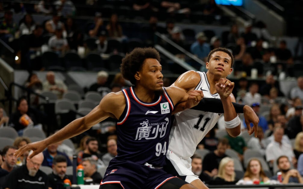 George King #94 of the Guangzhou Loong-Lions battles Carter Bryant #11 of the San Antonio Spurs in the second half in a preseason game at Frost Bank Center.