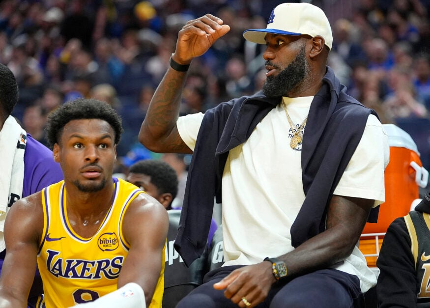 Bronny James #9 of the Los Angeles Lakers sits on the bench next to his father Lebron James #23 against the Golden State Warriors in the second half of a preseason NBA game at Chase Center.