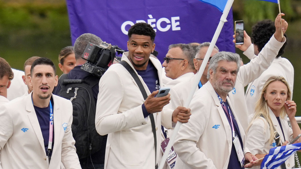 Giannis Antetokounmpo holds the Greek flag as their boat passes by during the Opening Ceremony for the Paris 2024 Olympic Summer Games.