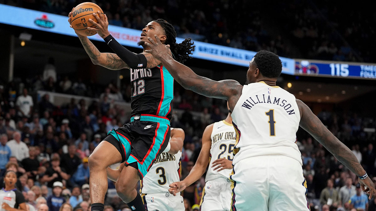 Grizzlies' Ja Morant (12) goes for a layup as Pelicans' Zion Williamson (1) guards him during the home opener against the New Orleans Pelicans at FedExForum on October 22, 2025.