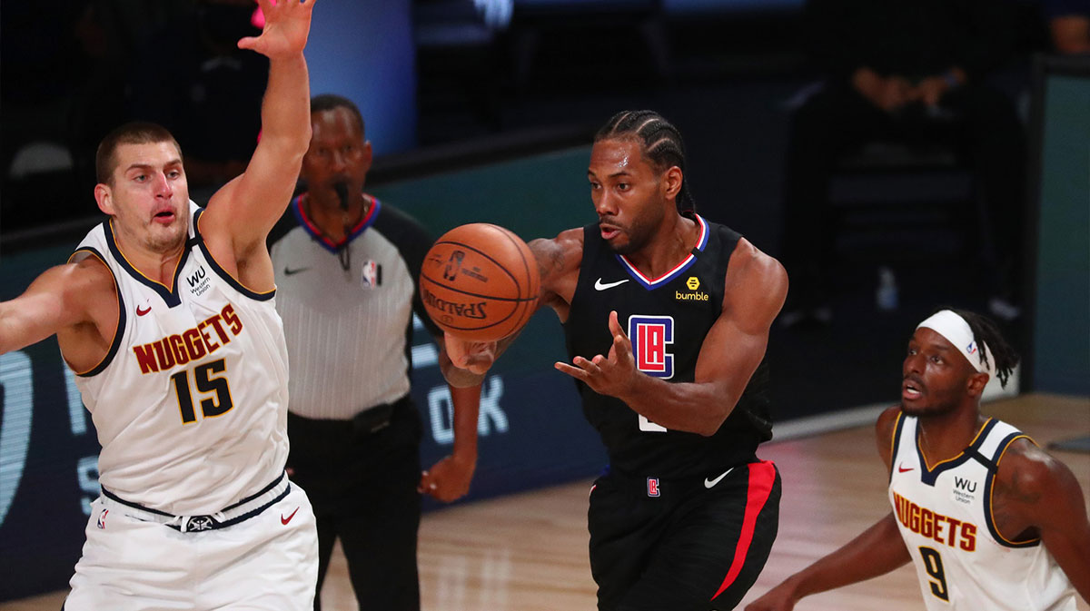 LA Clippers forward Kawhi Leonard (2) passes the ball between Denver Nuggets center Nikola Jokic (15) and forward Jerami Grant (9) during the first half of game two in the second round of the 2020 NBA Playoffs at AdventHealth Arena.