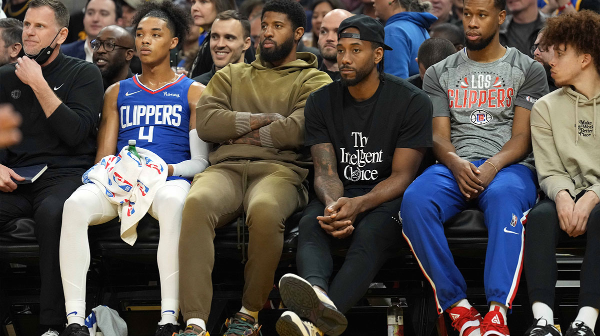 LA Clippers guard Paul George (center, left) and forward Kawhi Leonard (center, right) sit in street clothes on the bench during the second quarter against the Golden State Warriors at Chase Center.