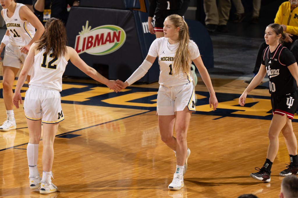 Michigan guards Olivia Olson and Syla Swords extend their right hands for a high-five during a game.