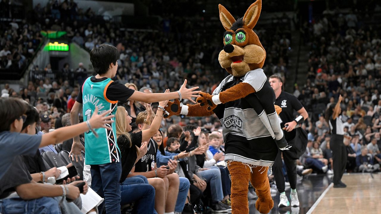 The Coyote, right, San Antonio Spurs' mascot, greets fans during the second half of an NBA basketball game against the Minnesota Timberwolves, Saturday, Nov. 2, 2024, in San Antonio. (AP Photo/Darren Abate)