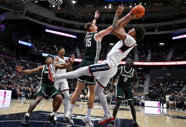 Michigan State center Carson Cooper (15) fouls UConn forward Jaylin Stewart during the first half of an NCAA basketball game, Tuesday, Oct. 28, 2025, at PeoplesBank Arena in Hartford, Conn. (AP Photo/Jessica Hill)