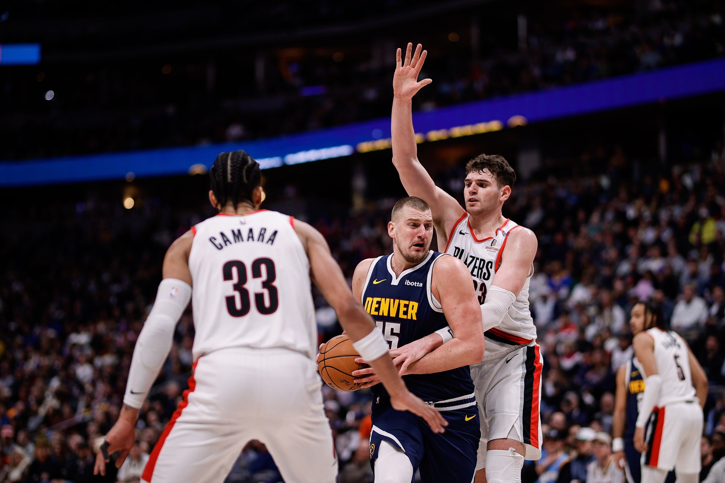 Feb 12, 2025; Denver, Colorado, USA; Denver Nuggets center Nikola Jokic (15) is fouled by Portland Trail Blazers center Donovan Clingan (23) as forward Toumani Camara (33) defends in the third quarter at Ball Arena.