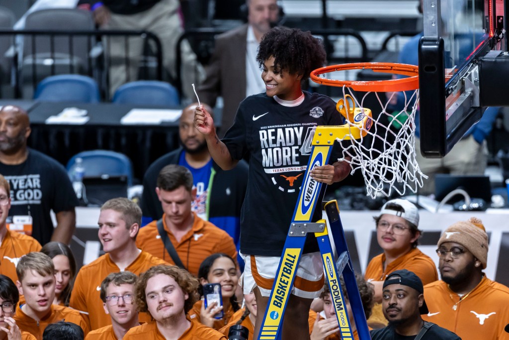 Rori Harmon stands on a ladder and holds up the piece of net she just cut as Texas celebrates its trip to the Final Four.