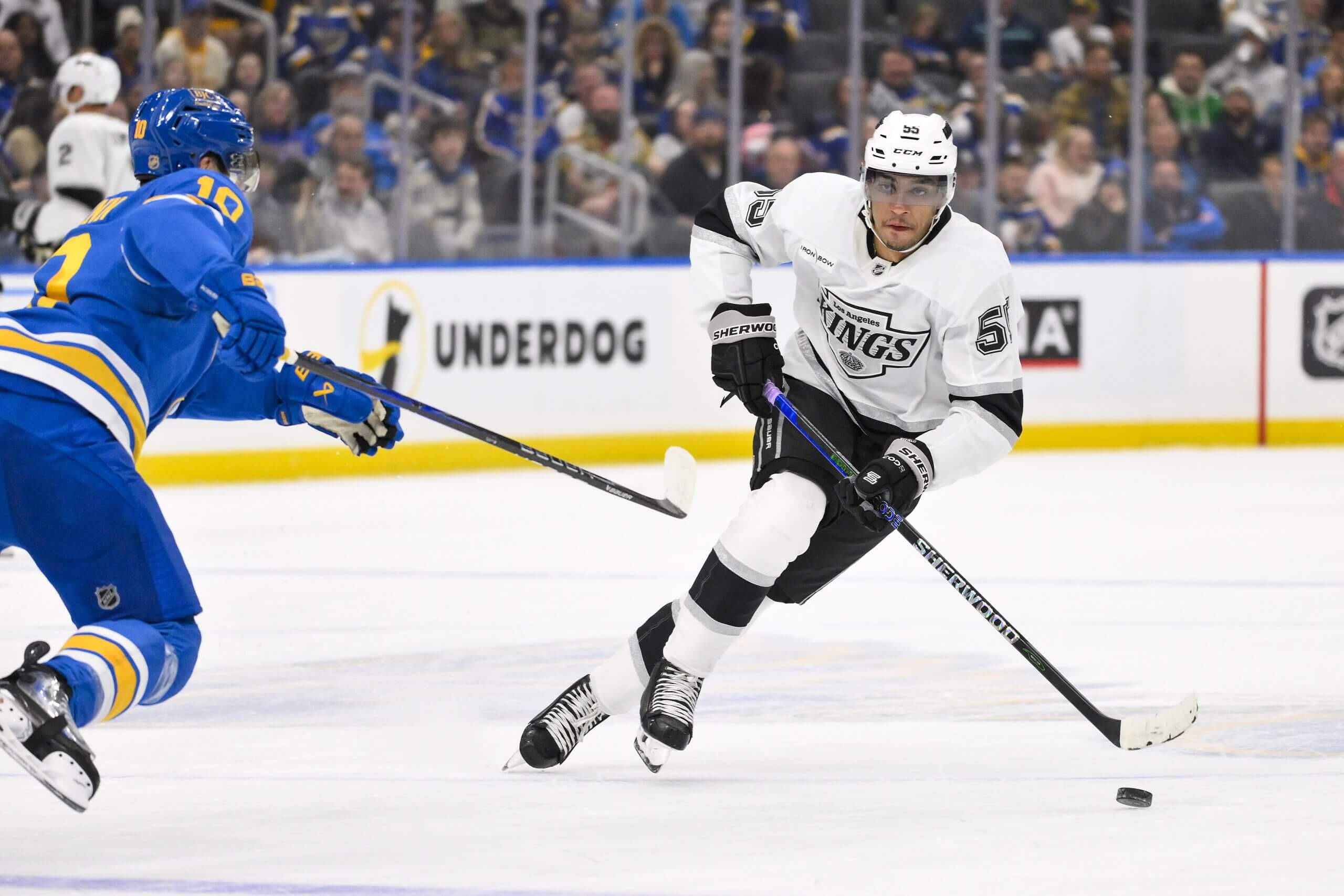 Quinton Byfield skates down the ice with the puck while a St. Louis Blues player tries to intercede.