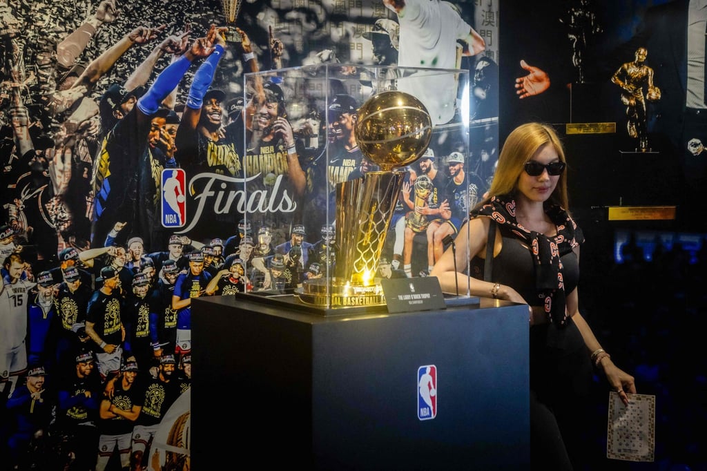 A tourist poses next to the NBA Championship trophy at the NBA House. Photo: AFP