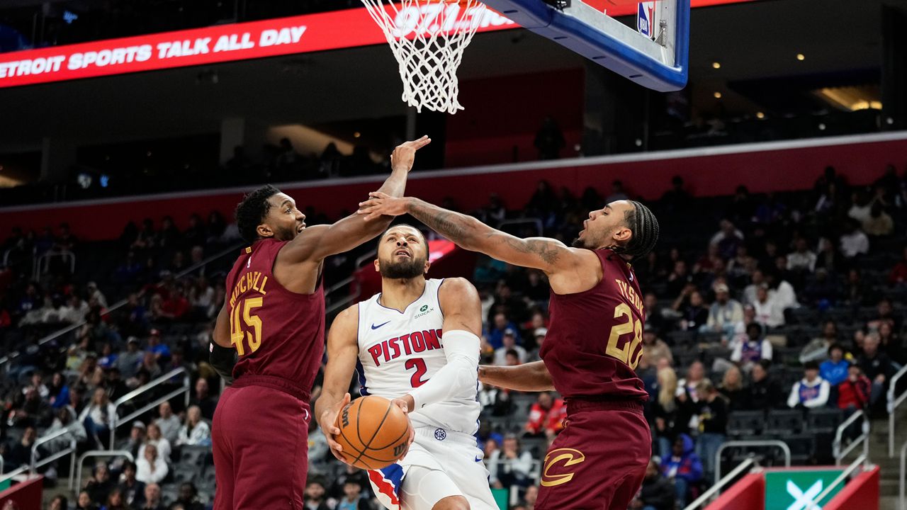 Detroit Pistons guard Cade Cunningham, center, shoots against Cleveland Cavaliers guards Donovan Mitchell, left, and Jaylon Tyson during the first half of an NBA basketball game, Monday, Oct. 27, 2025, in Detroit. (AP Photo/Ryan Sun)