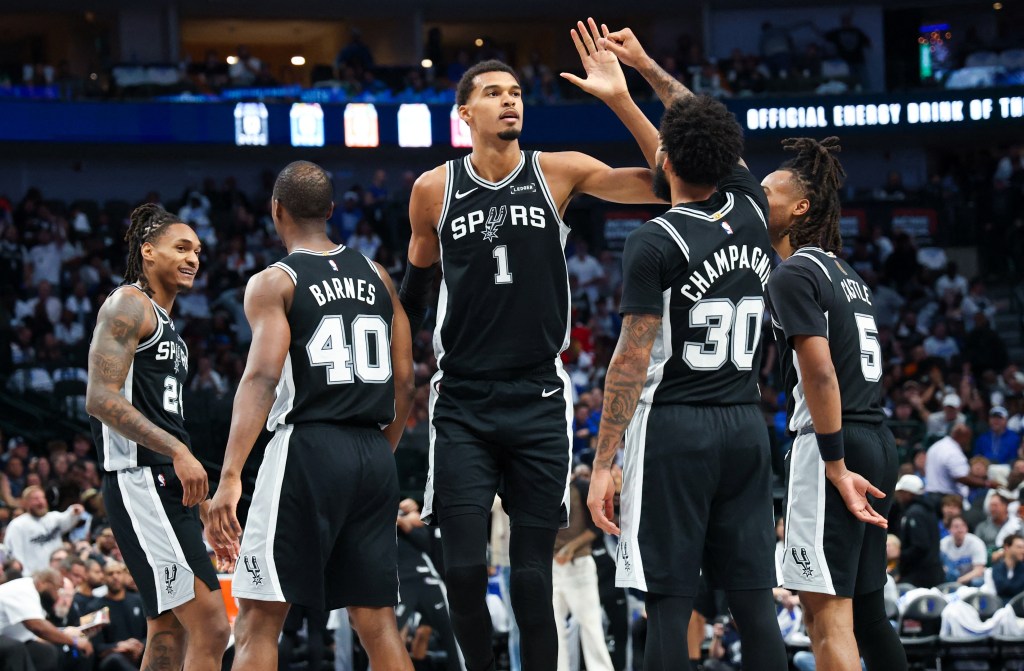 Oct 22, 2025; Dallas, Texas, USA; San Antonio Spurs forward Victor Wembanyama (1) celebrates with San Antonio Spurs forward Julian Champagnie (30) and San Antonio Spurs guard Stephon Castle (5) and San Antonio Spurs forward Harrison Barnes (40) during the second half against the Dallas Mavericks at American Airlines Center