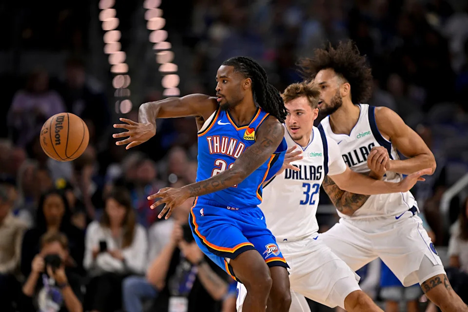 Oct 6, 2025; Fort Worth, Texas, USA; Oklahoma City Thunder guard Cason Wallace (22) passes the ball by Dallas Mavericks forward Cooper Flagg (32) and center Dereck Lively II (2) during the first quarter at Dickie's Arena. Mandatory Credit: Jerome Miron-Imagn Images