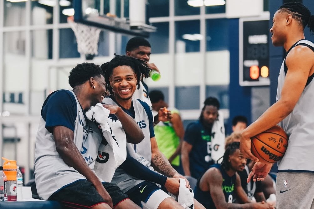 Anthony Edwards and Terrence Shannon Jr sitting on scorers table laughing, Jaylen Clark laughing standing across from them