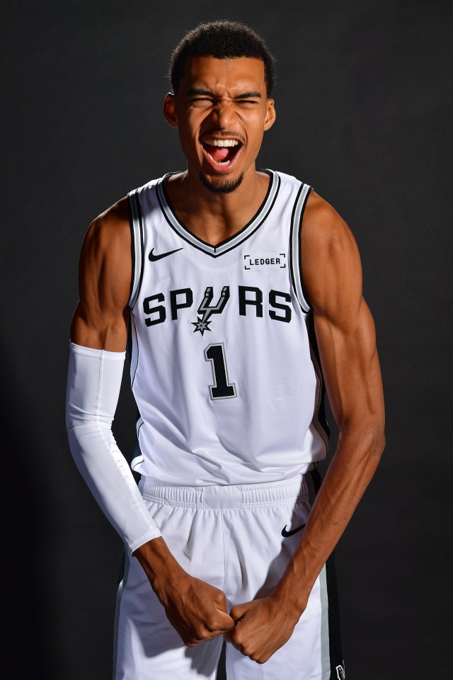 Victor Wembanyama flexes his muscles in a sleveless jersey