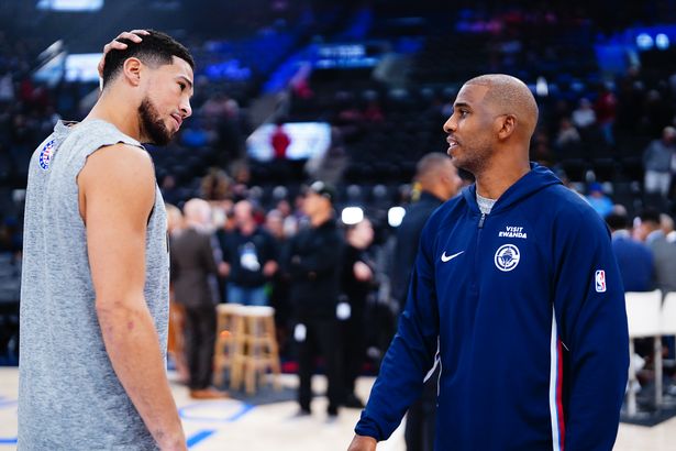 Devin Booker #1 of the Phoenix Suns and Chris Paul #3 of the LA Clippers talk before the game on November 9, 2025 at Crypto.Com Arena in Los Angeles, California
