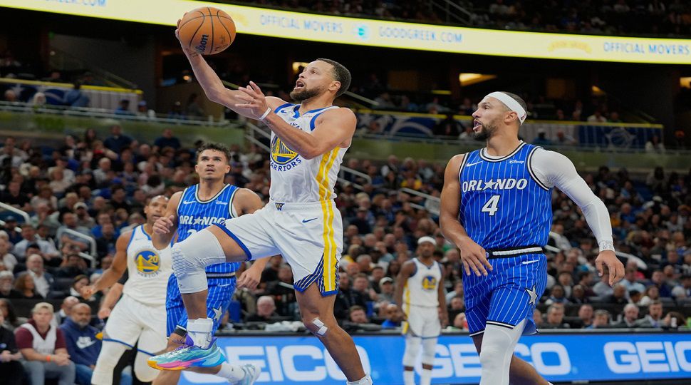 Golden State Warriors guard Stephen Curry, center, gets past Orlando Magic guard Jalen Suggs (4) and forward Tristan da Silva, left, during the second half of an NBA basketball game, Tuesday, Nov. 18, 2025, in Orlando, Fla. (AP Photo/John Raoux)