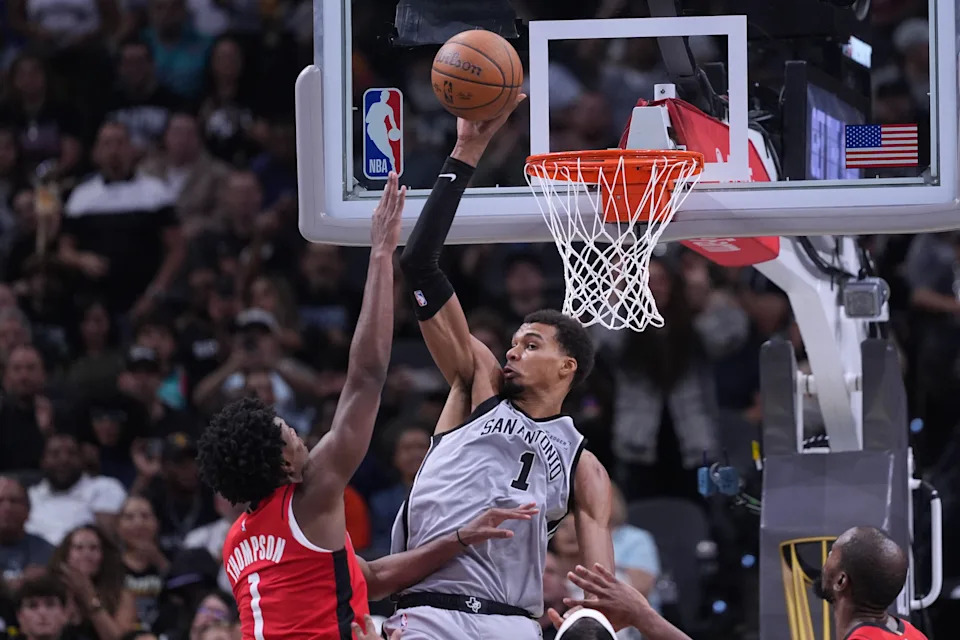 San Antonio Spurs forward Victor Wembanyama, center, reaches for a pass over Houston Rockets guard Amen Thompson, left, during the second half of an NBA Cup basketball game in San Antonio, Friday, Nov. 7, 2025. (AP Photo/Eric Gay)