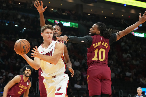 Miami Heat guard Pelle Larsson (9) passes the ball under pressure from Cleveland Cavaliers guard Darius Garland (10) and center Evan Mobley during the first half of an NBA basketball game Monday, Nov. 10, 2025, in Miami. (AP Photo/Marta Lavandier)