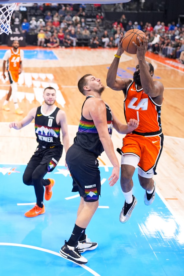 Clippers guard James Harden, right, shoots as Denver Nuggets center...