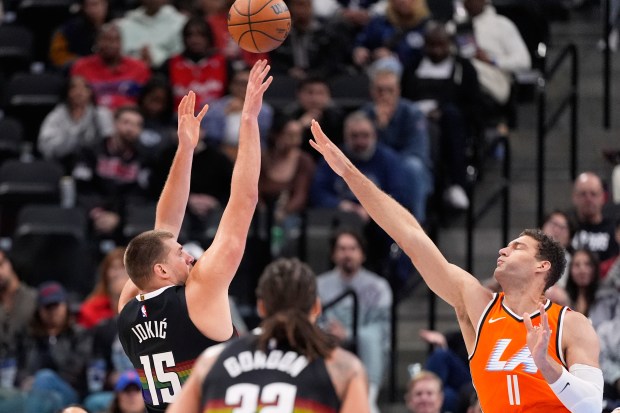 Denver Nuggets center Nikola Jokic, left, shoots as Clippers center...