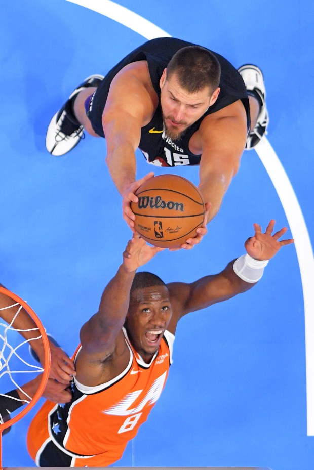 Denver Nuggets center Nikola Jokic, top, and Clippers guard Kris...