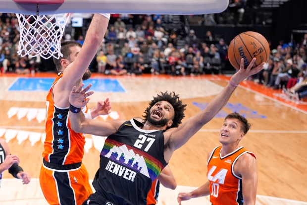 Denver Nuggets guard Jamal Murray, center, shoots as Clippers center...